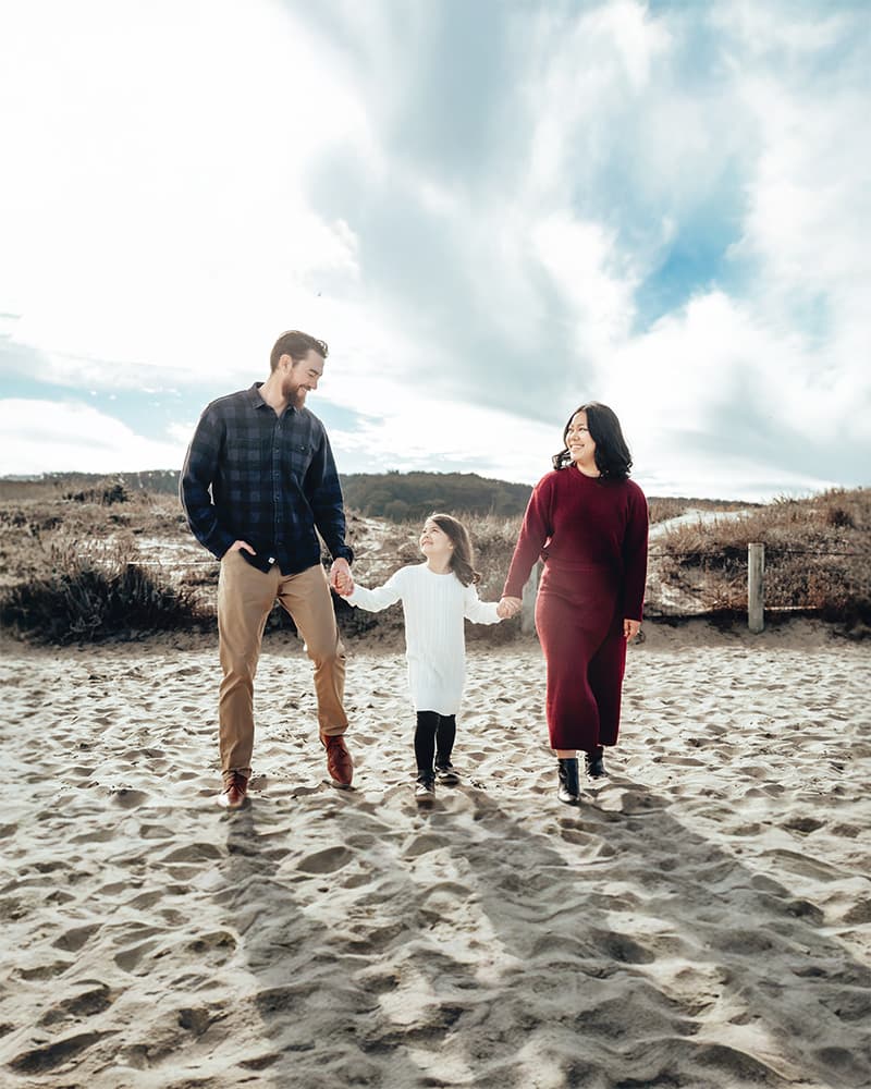 Family portrait photography — parents embracing their children in warm natural light